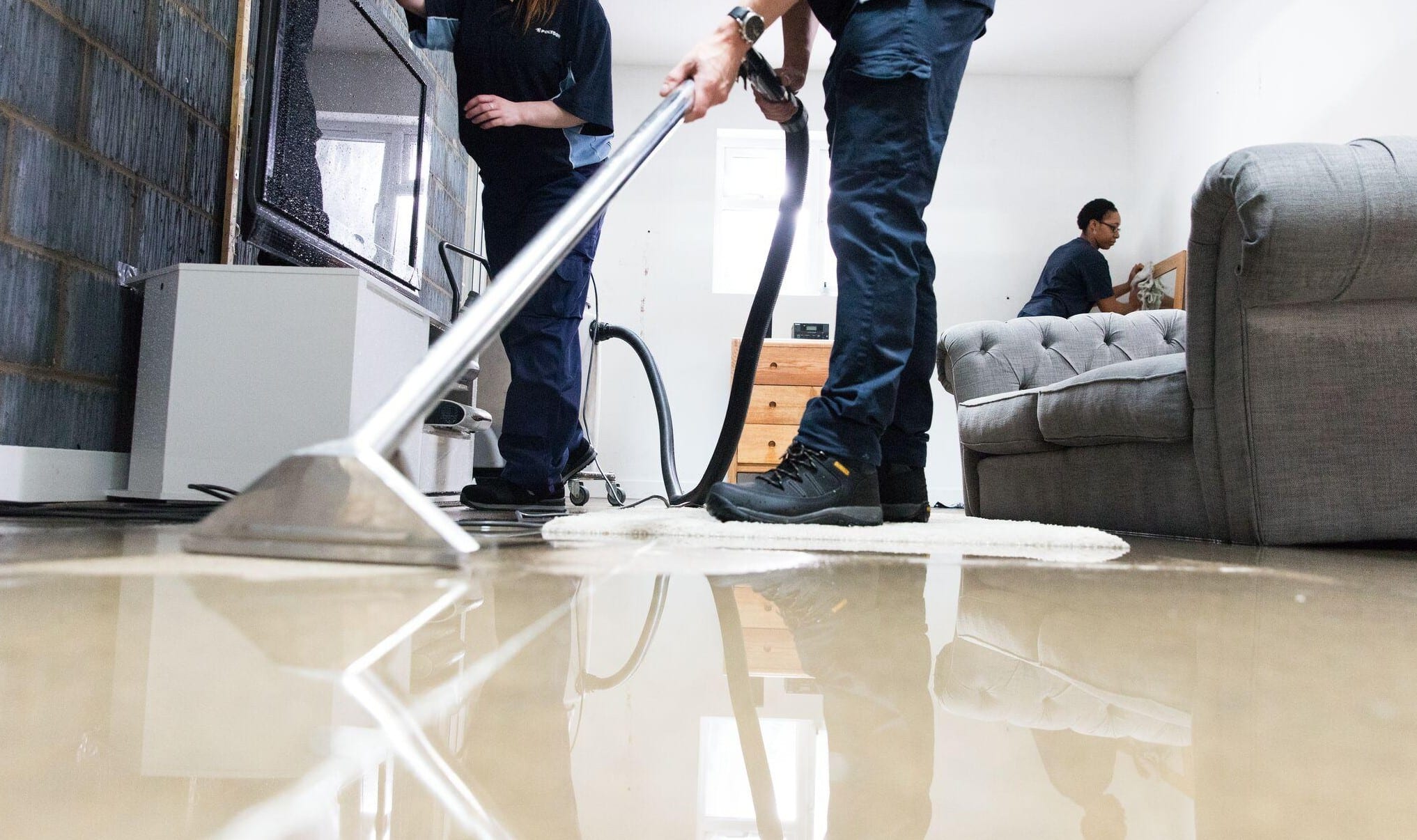 Restoration crew extracting standing water from a flooded living room floor